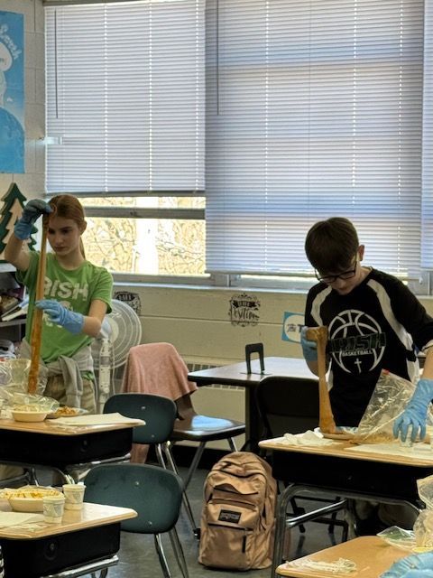 Two students in a classroom pulling taffy, wearing gloves.