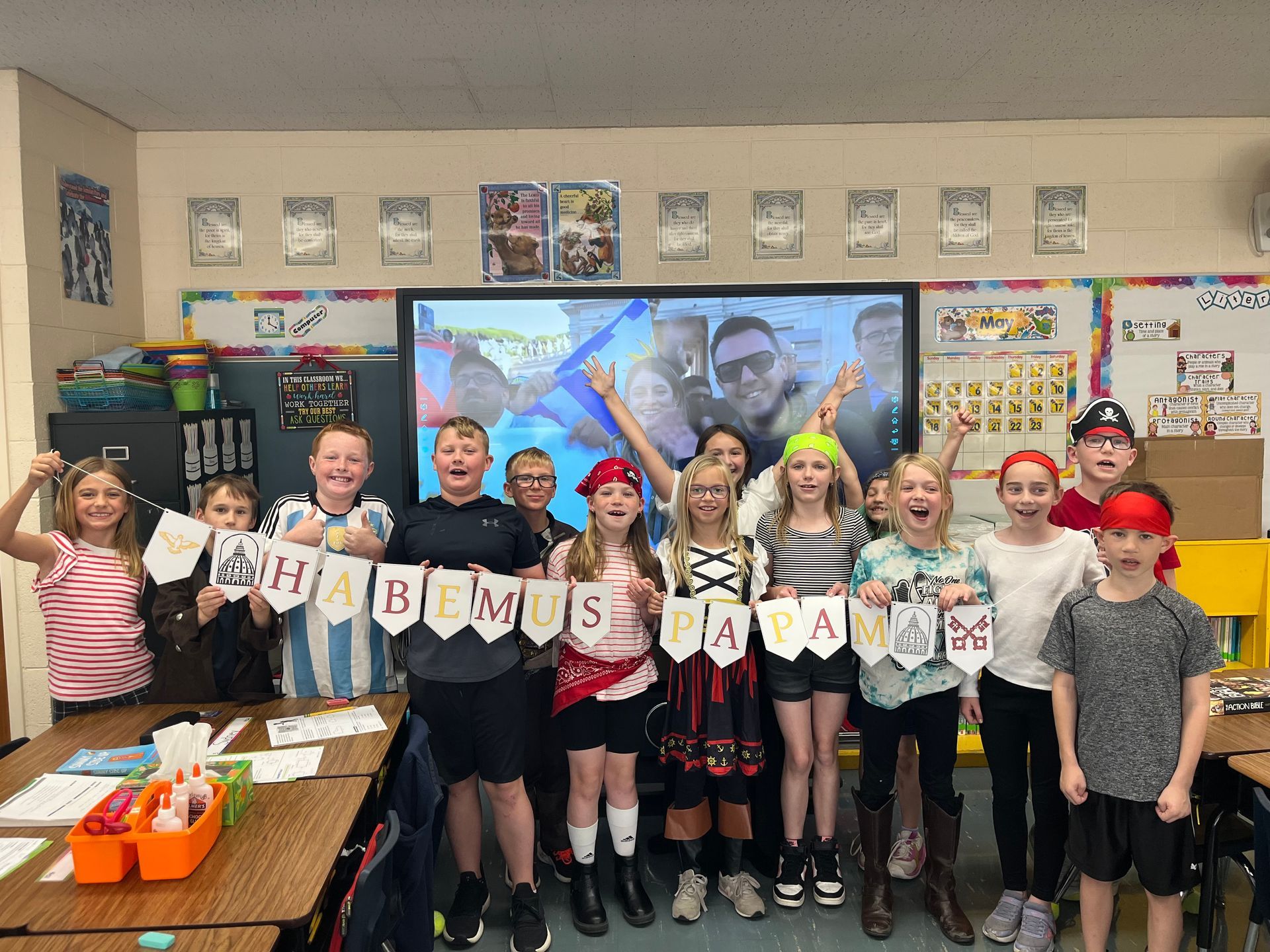 Group of students dressed as pirates in a classroom, holding a banner that reads 