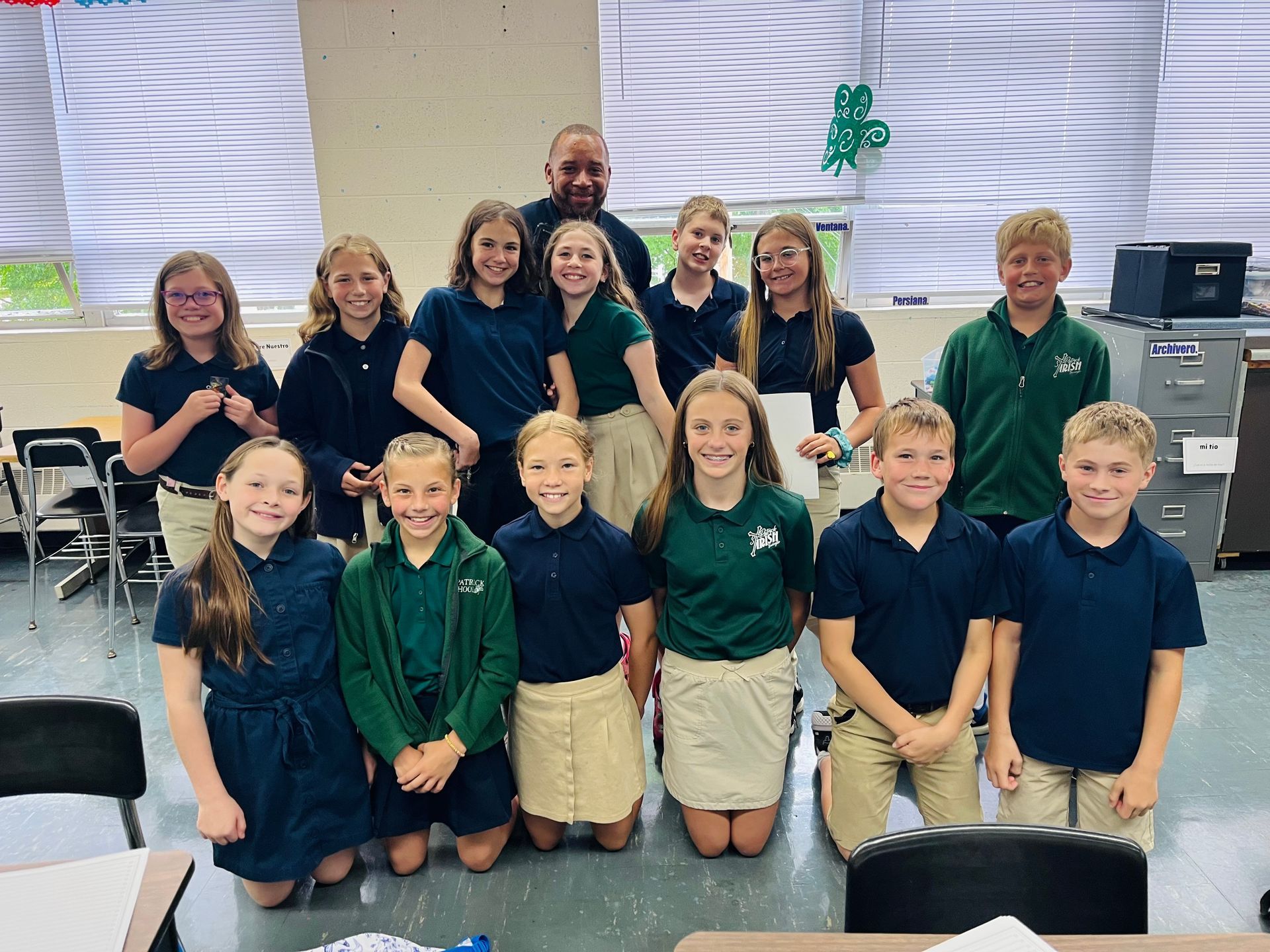 Group photo of students in school uniforms and a teacher in a classroom.