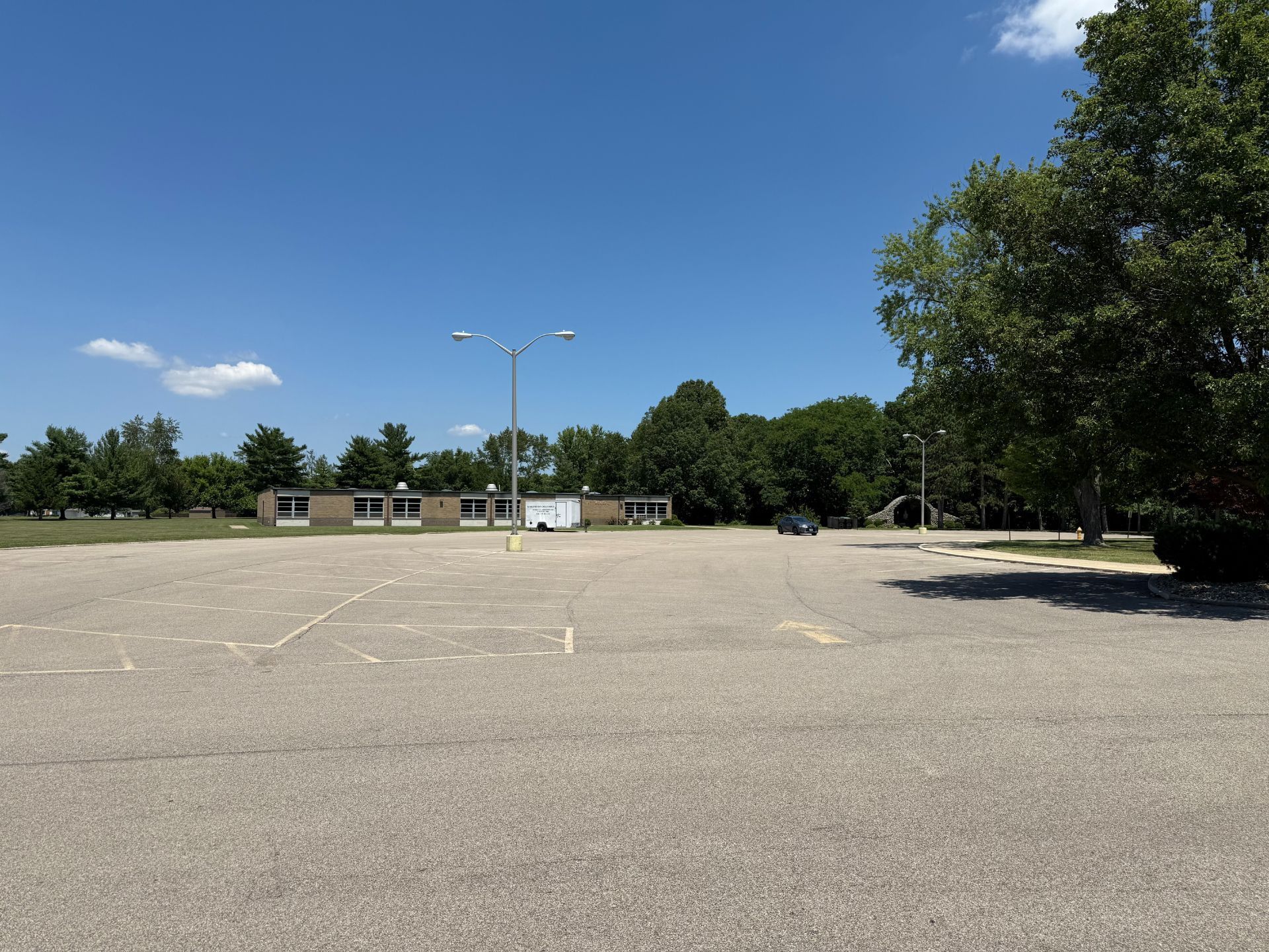 Paved parking lot in front of a one-story building under a bright blue sky.