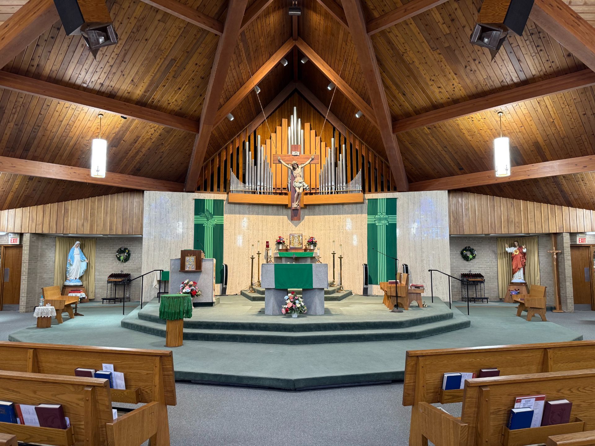 Interior of a church sanctuary with altar, crucifix, and pews, with green and wood tones.