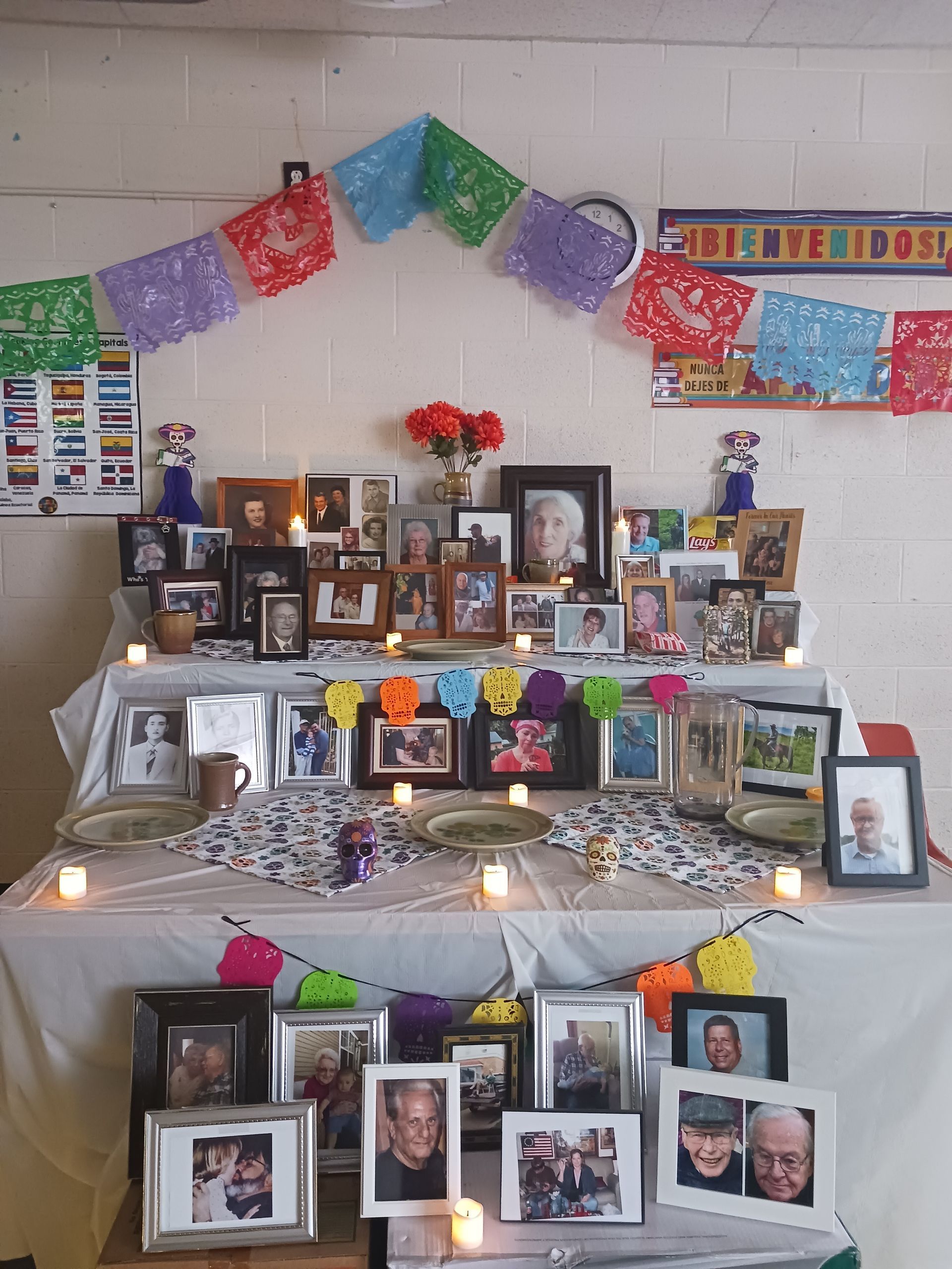 Day of the Dead altar with photos, candles, flowers, and papel picado decorations.