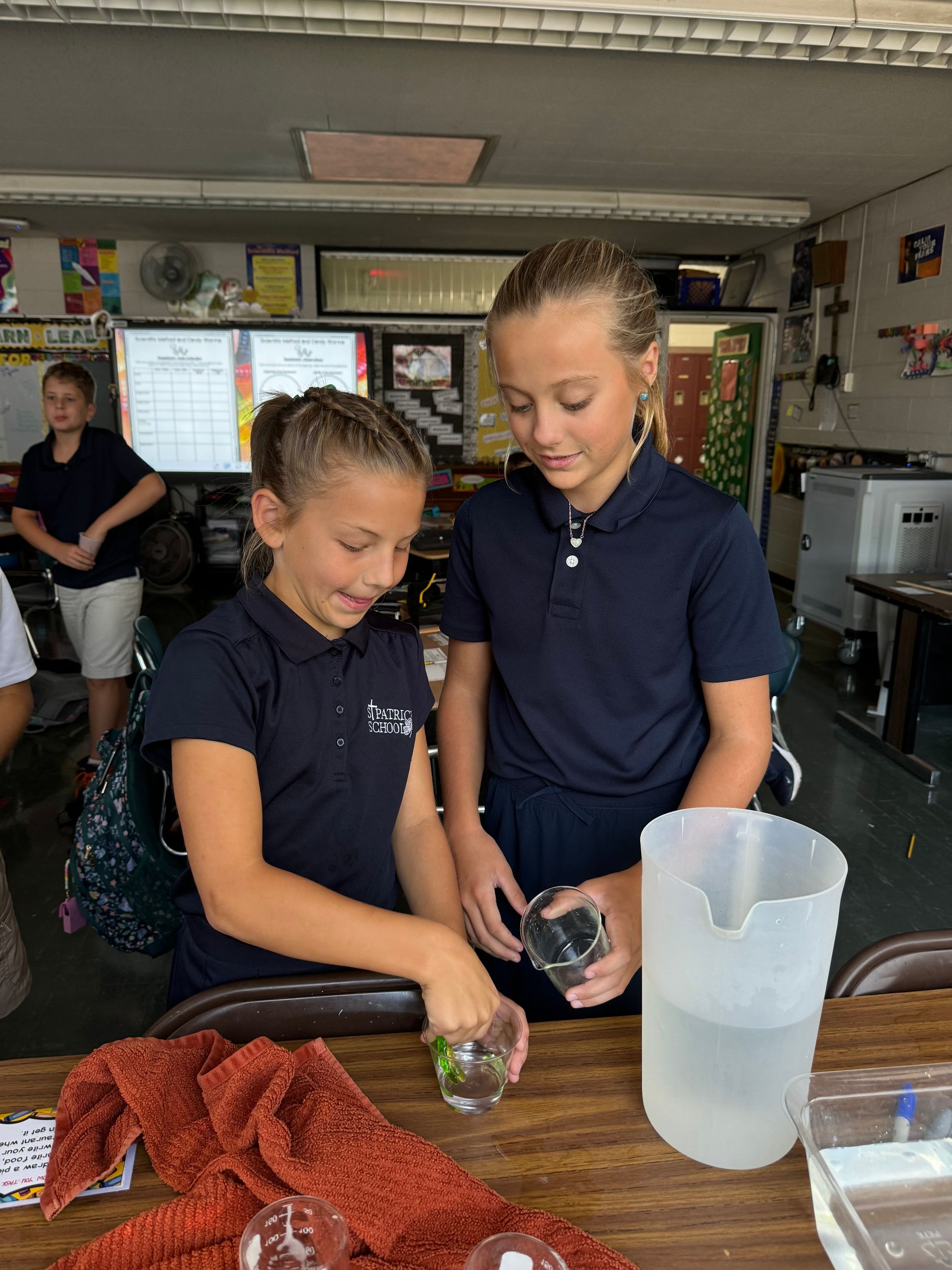 Two girls in school uniforms do a science experiment with water.