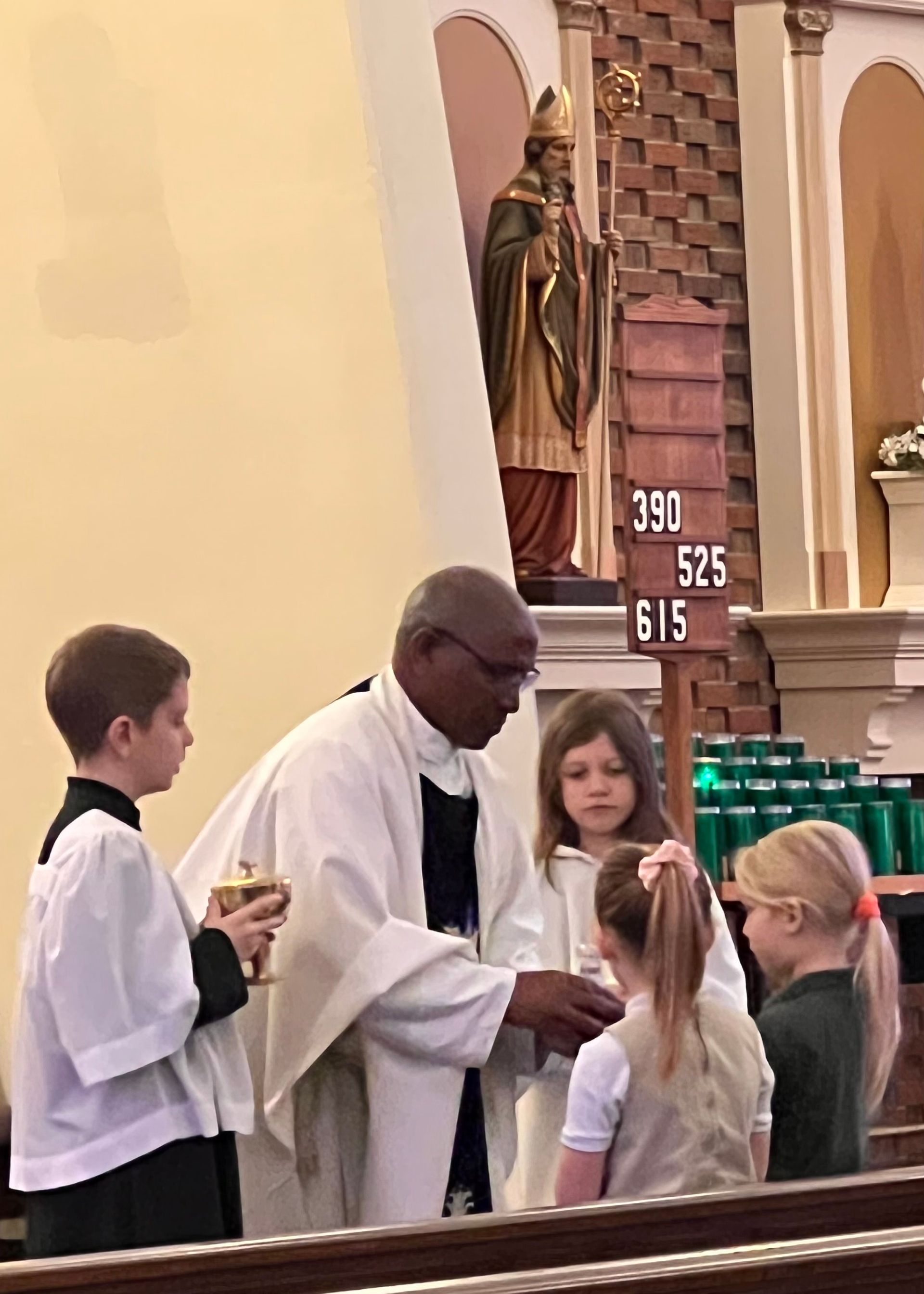 Priest giving communion to children at a church.