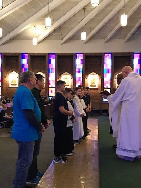 Group of people in a church. Priests and boys in white robes stand near the altar during a religious ceremony.