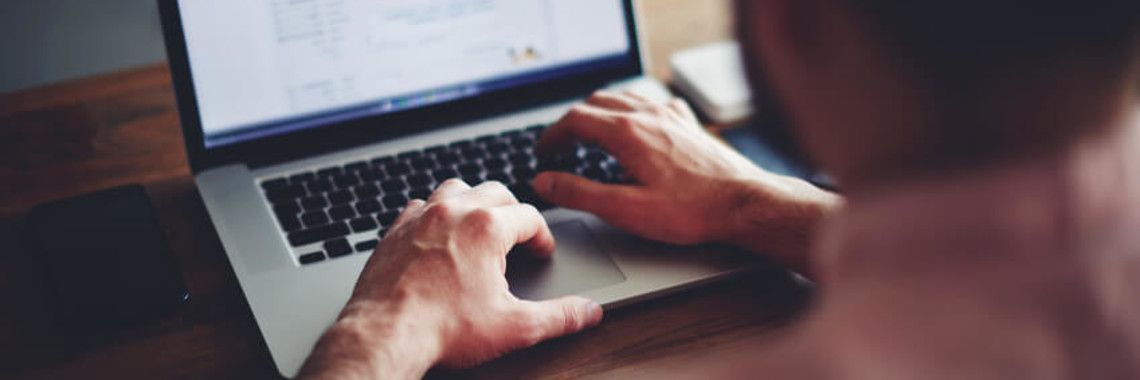 Person typing on a laptop, close-up of hands and screen.