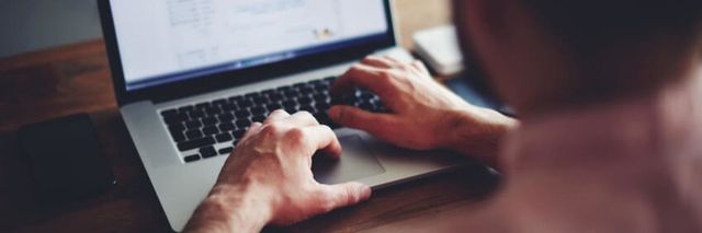 Person typing on a laptop, close-up of hands and screen.