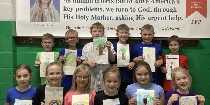 Children hold artwork; group in front of a banner that references God and the Virgin Mary.