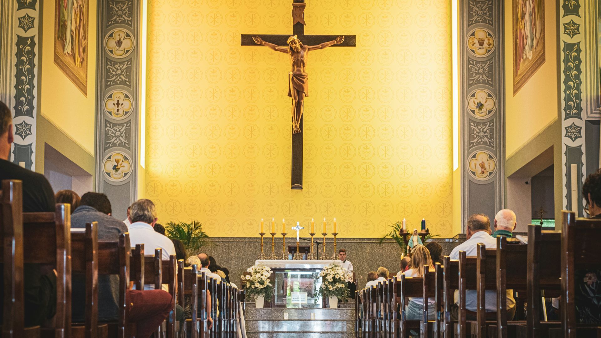Church interior with people in pews facing an altar with a crucifix.
