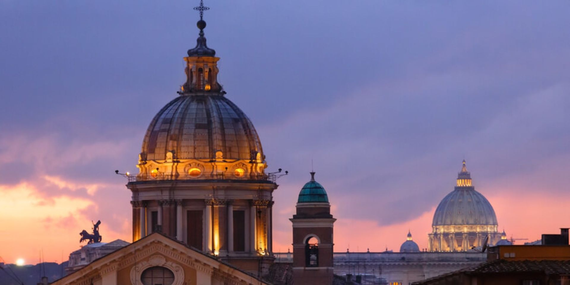 View of church domes at dusk with purple and orange sky.