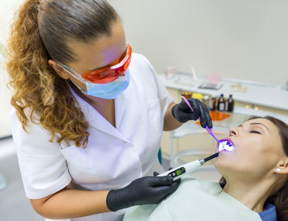 Dentist using curing light on a patient’s tooth in a dental clinic.