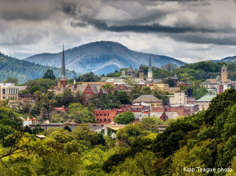 Couple reviewing paperwork with a professional in a home. The woman embraces the man while the other woman holds documents.