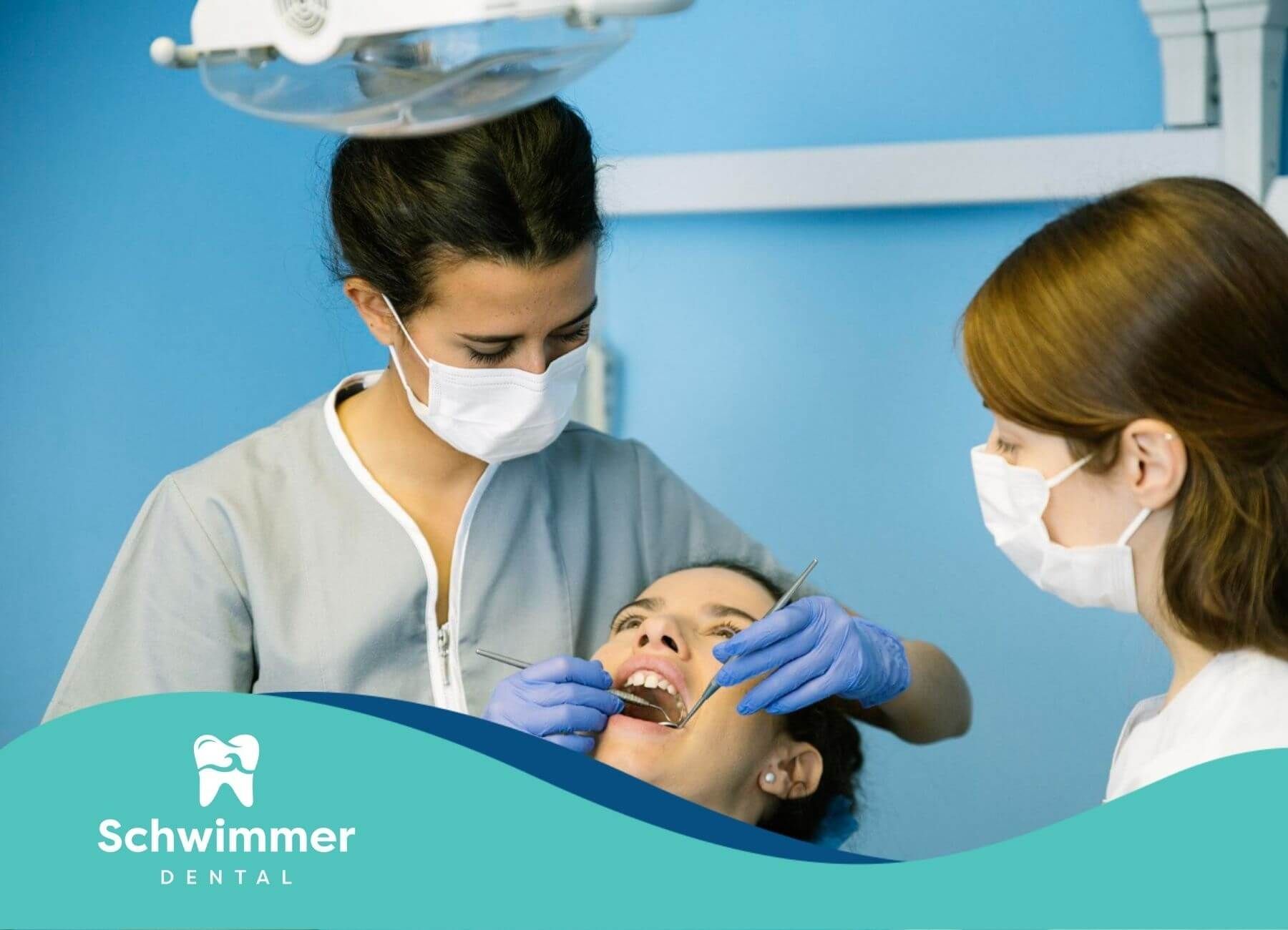 Dentist and assistant examining a patient’s teeth during checkup.