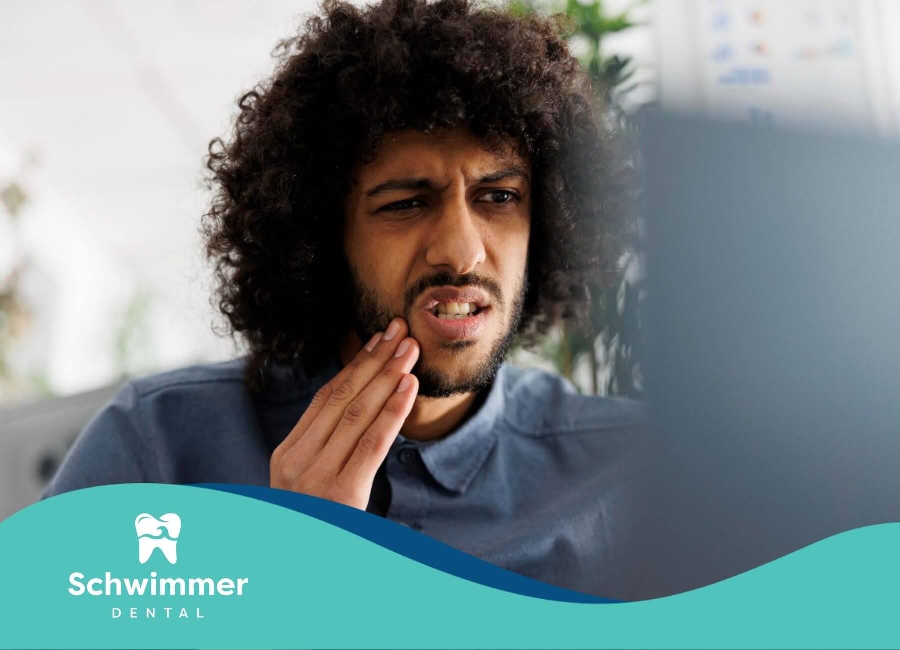Man holding his cheek in pain from toothache.