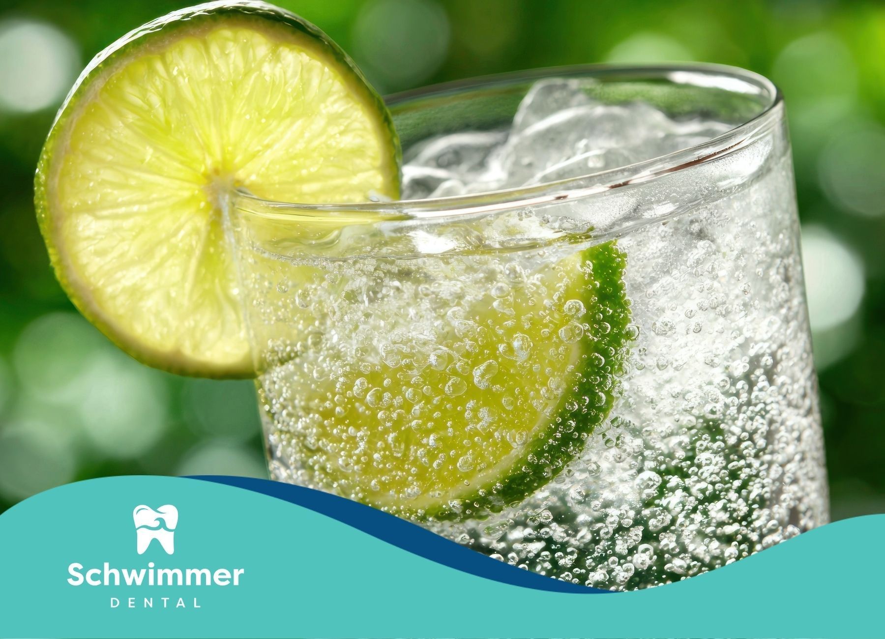 Glass of fizzy drink with lime slices and ice, with green background.