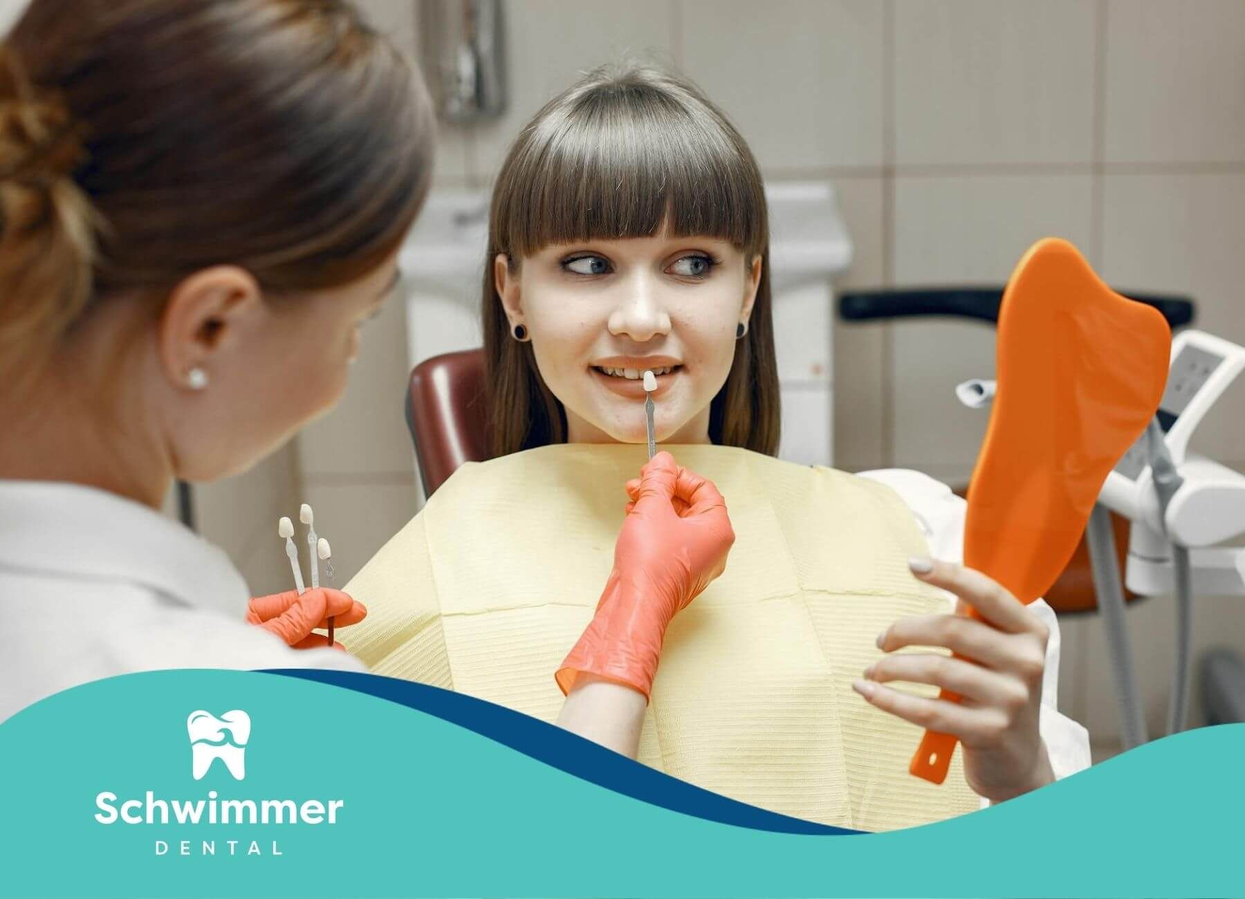Female dentist showing veneer samples to patient holding a mirror in clinic chair in New Jersey