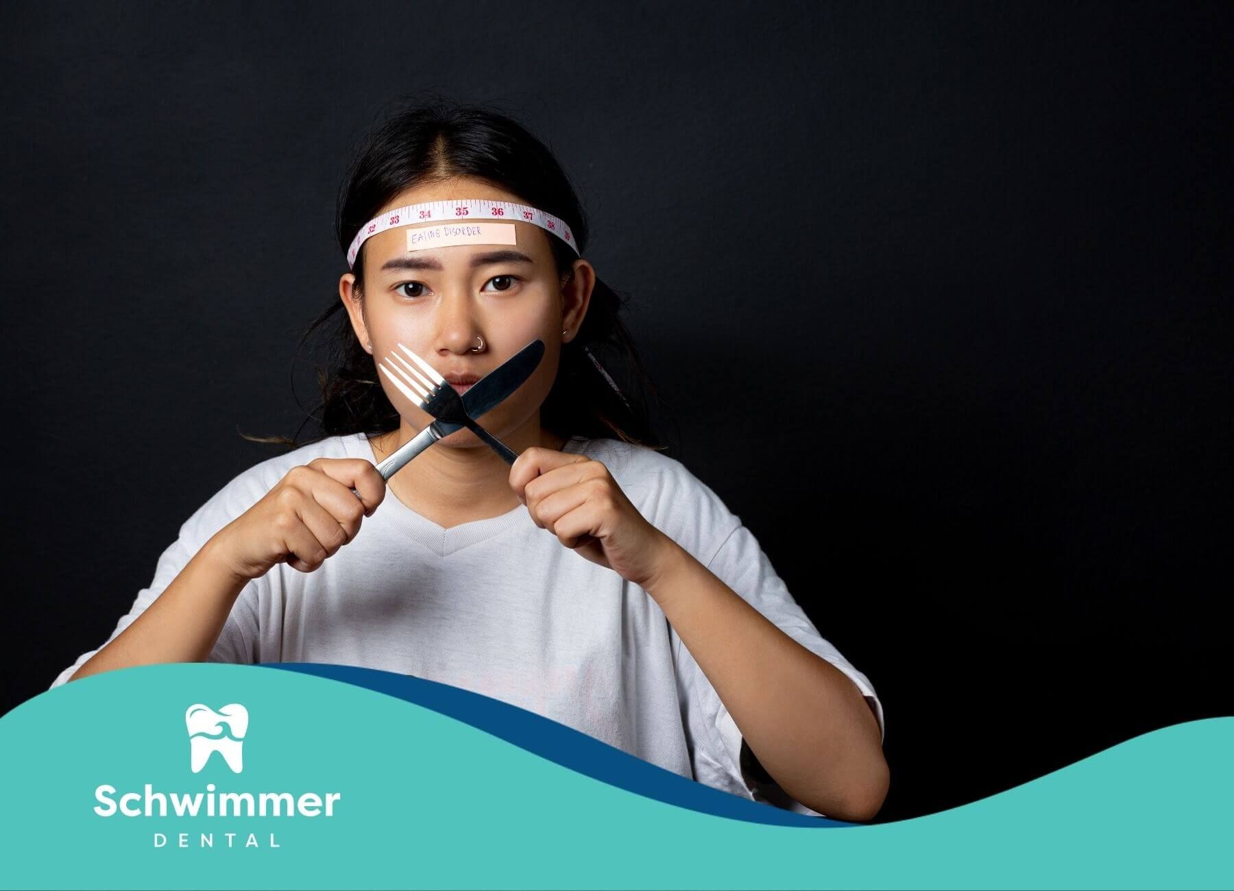 A young woman holding a fork and knife, both crossed in front of her mouth, with a measuring tape