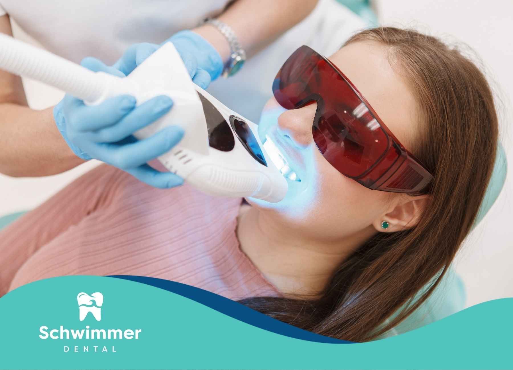 A woman is getting her teeth whitened by a dentist.