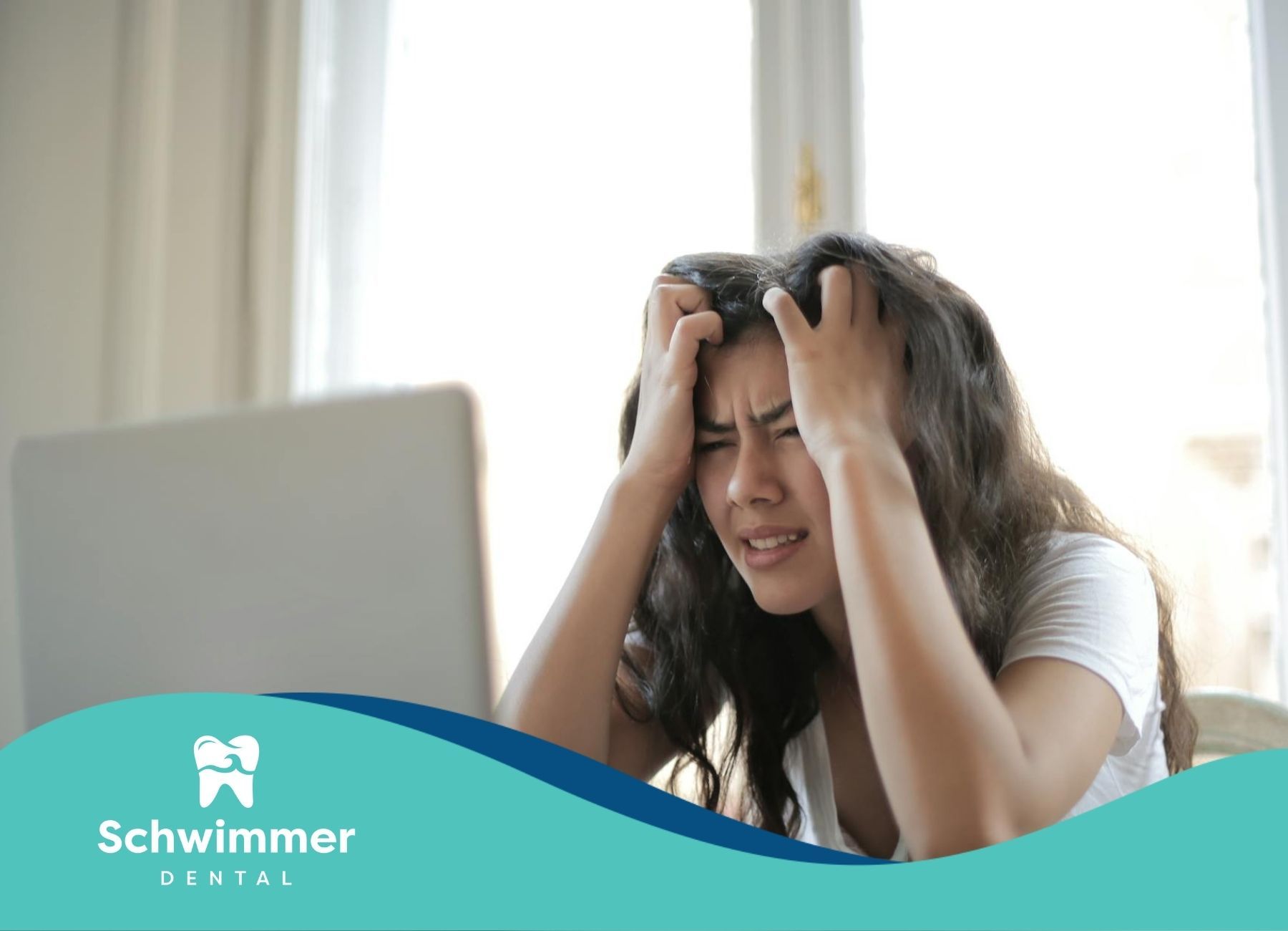 A stressed woman, grabbing her hair while sitting at a desk with a laptop in Point Pleasant Beach NJ