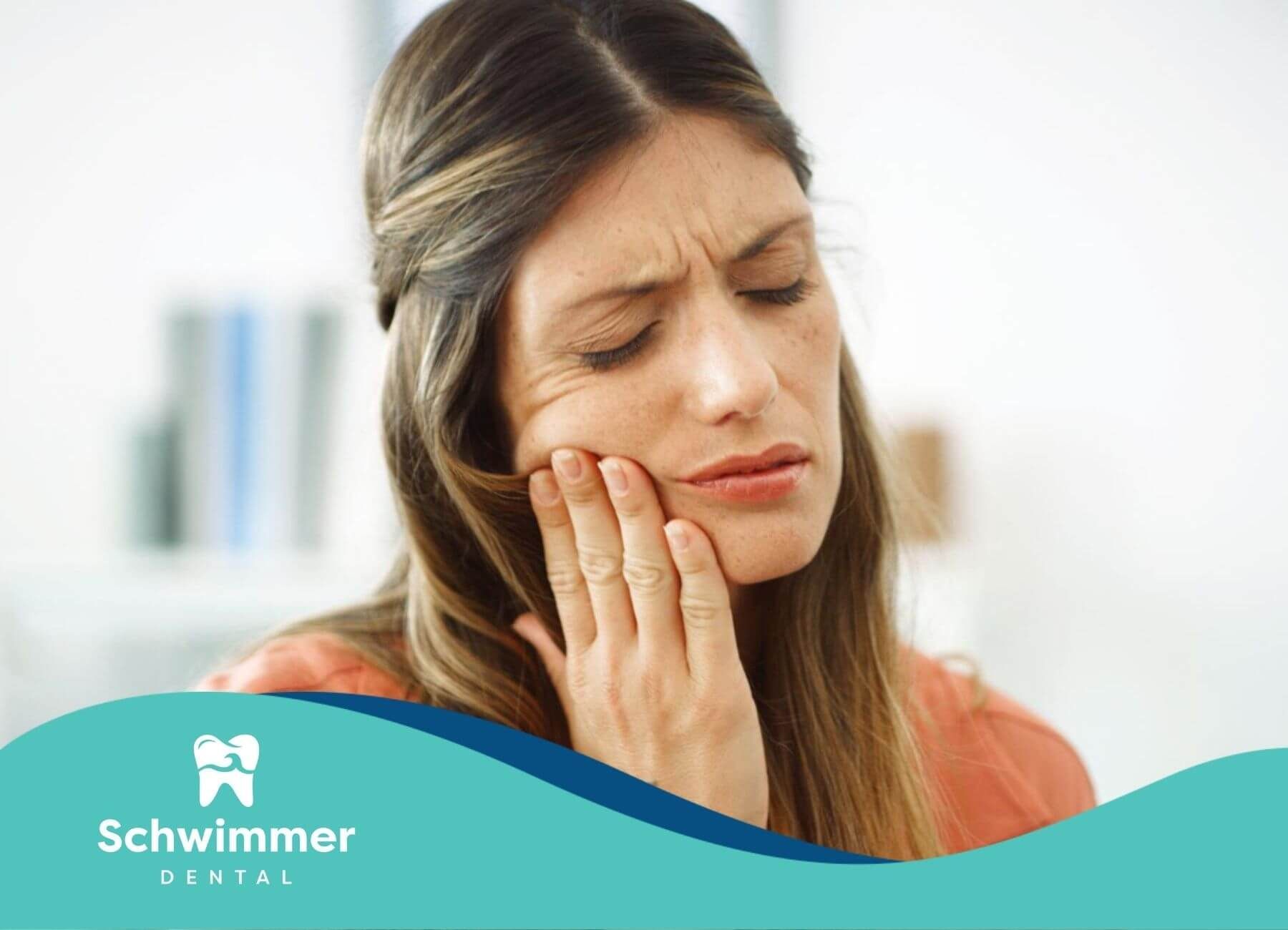 Woman with hand on jaw suffering from dental pain.
