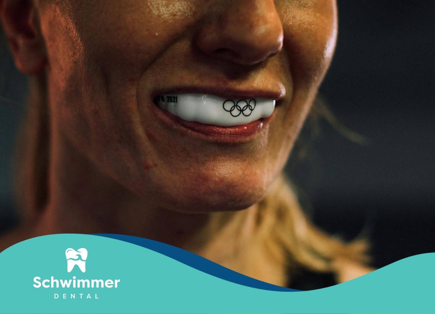 A patient woman wearing a mouth guard with Olympic rings design while smiling after dental treatment