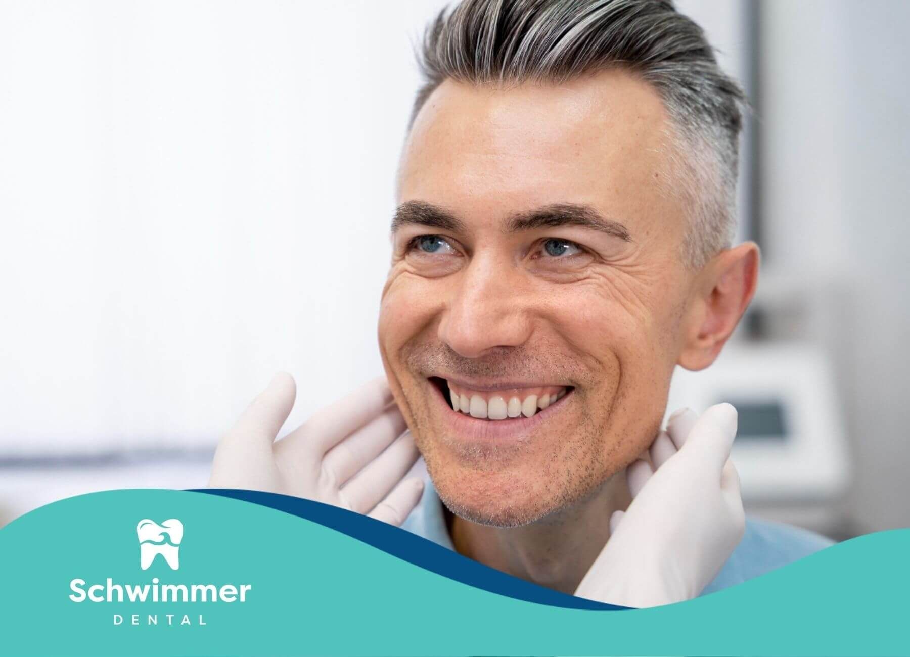 A man is smiling while a dentist examines his teeth.