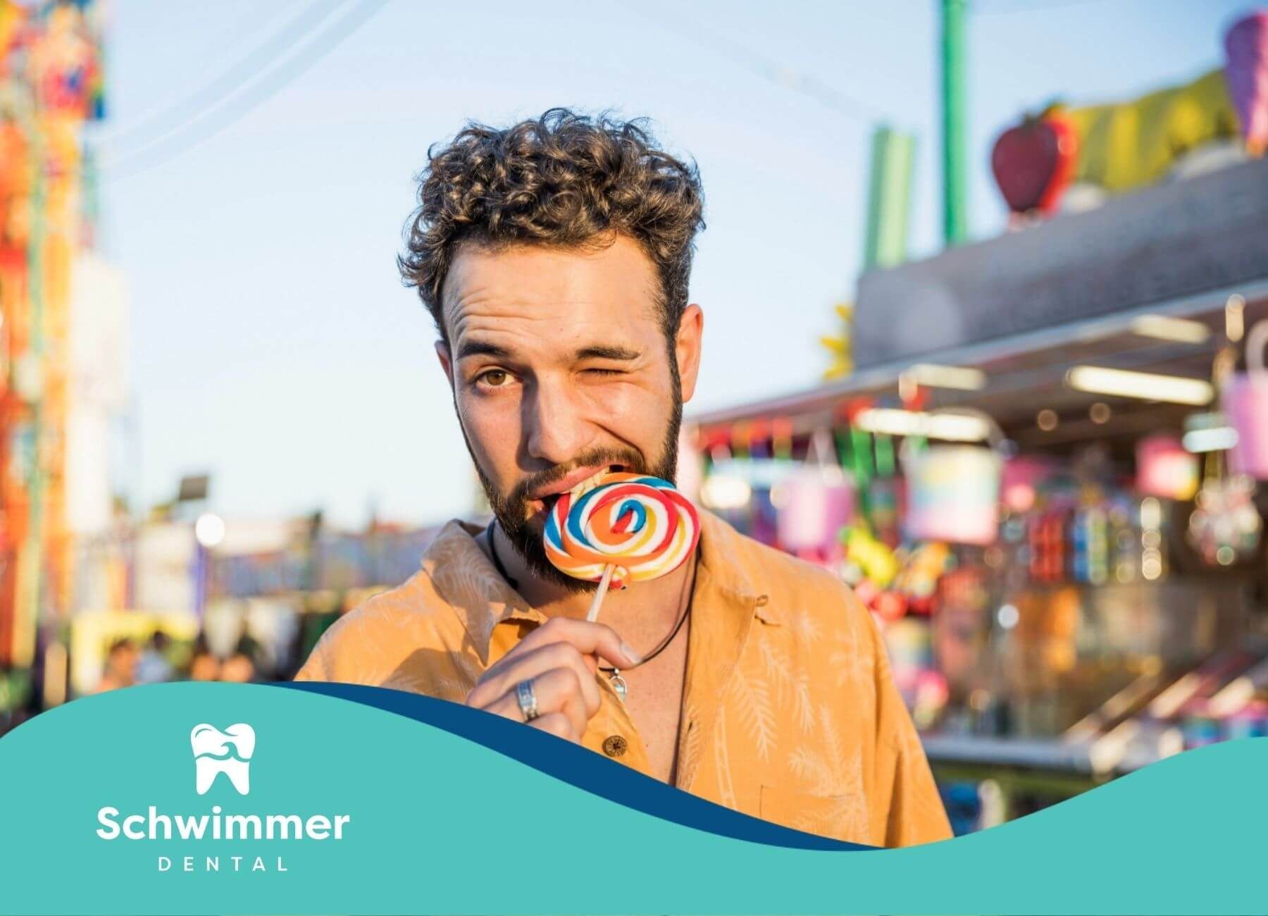 Man eating colorful lollipop at outdoor fair.
