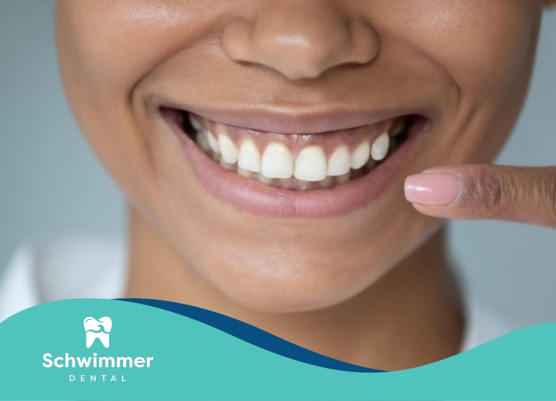 A woman pointing to her healthy white smile, showing her good oral health after checkup in NJ.
