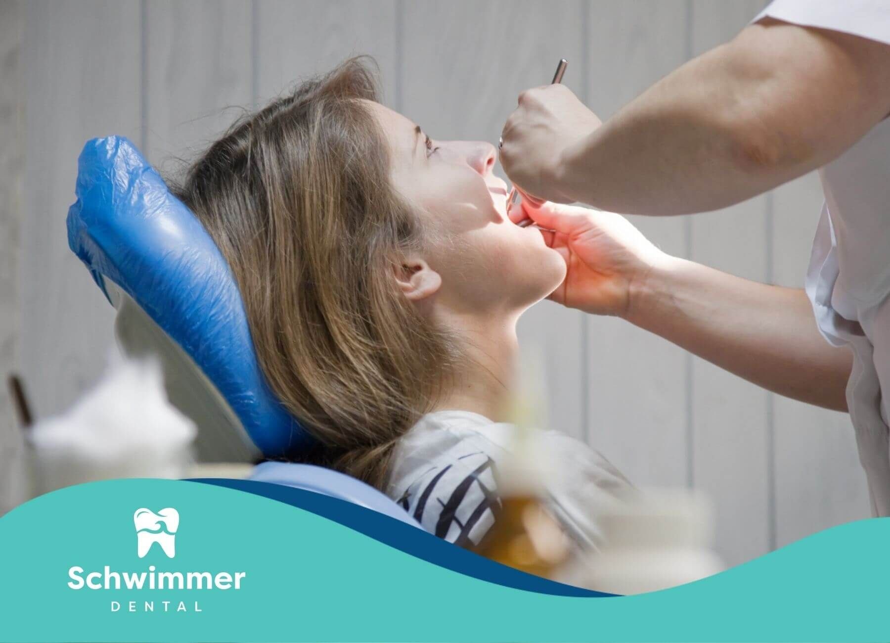 A woman is sitting in a dental chair getting her teeth examined by a dentist.