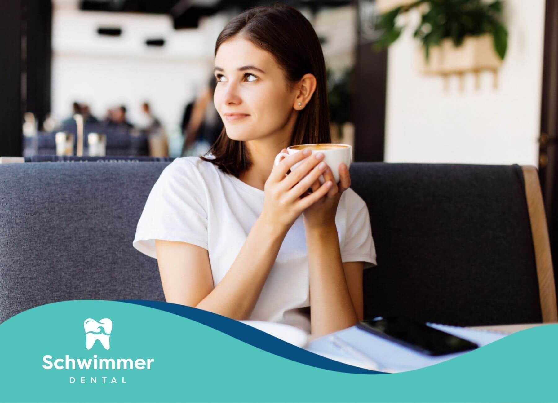 Woman sitting in a café holding a cup of coffee.
