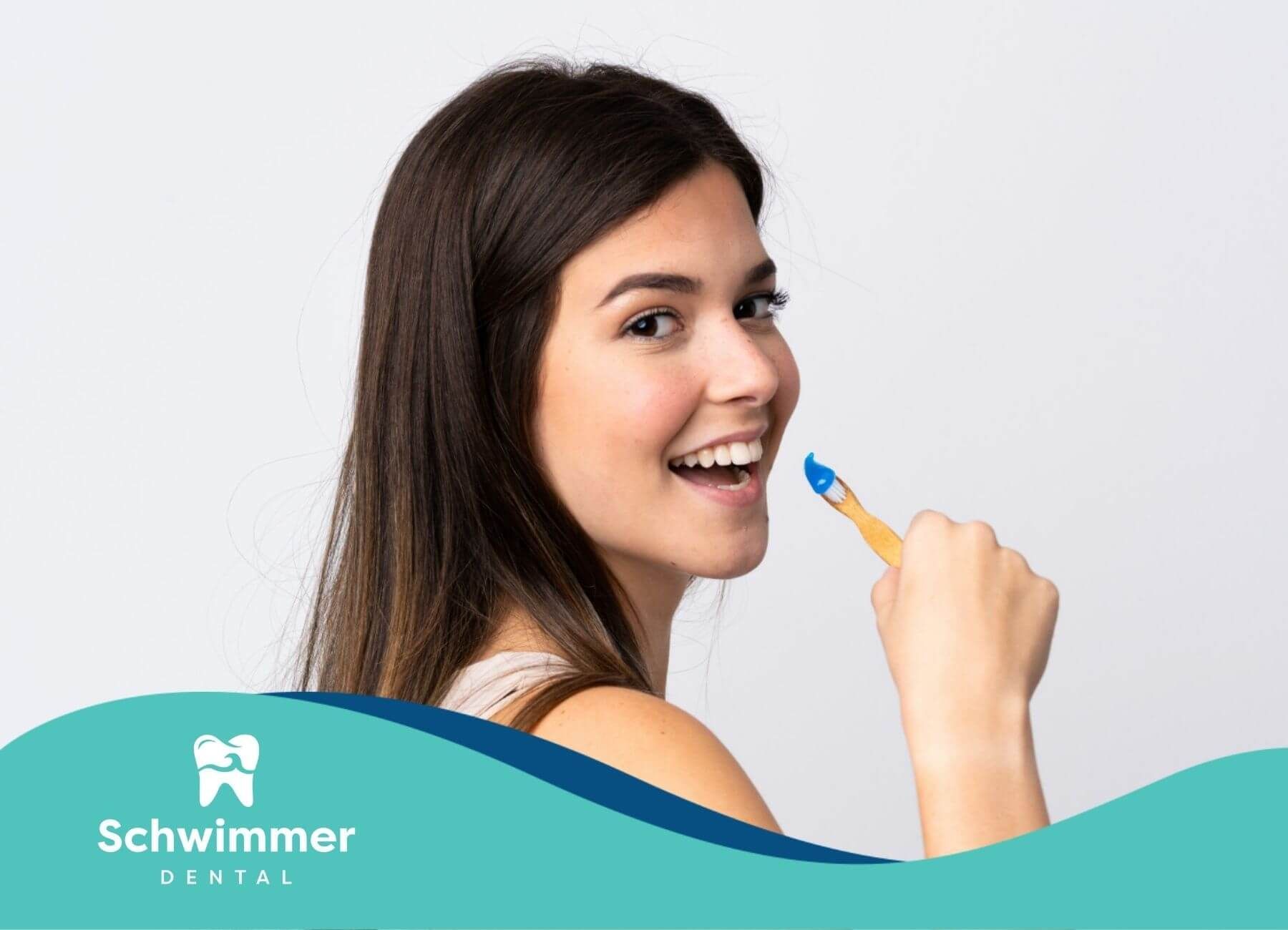 Smiling woman holding toothbrush with toothpaste.