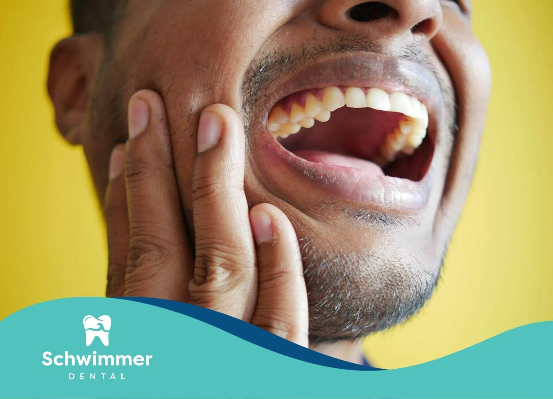 Man pressing his cheek in visible discomfort, showing signs of intense pain from a severe toothache.