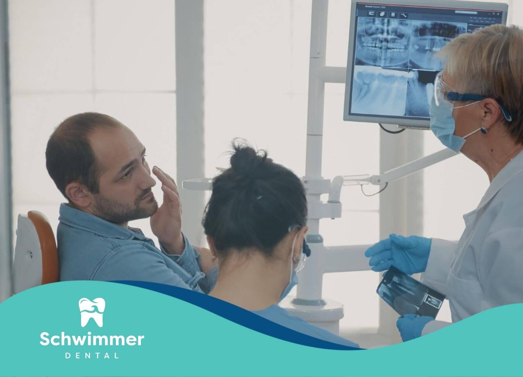 Dentist examining a patient's teeth while displaying dental X-rays in a clinic setting.