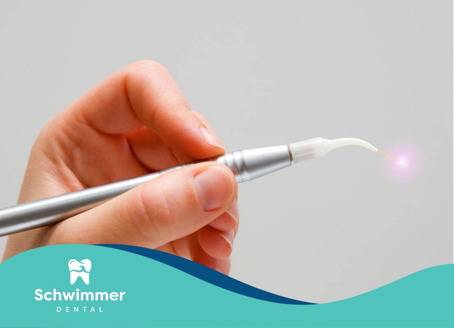 Hand of a dentist holding a dental laser tool with a glowing pink tip in Point Pleasant Beach, NJ.