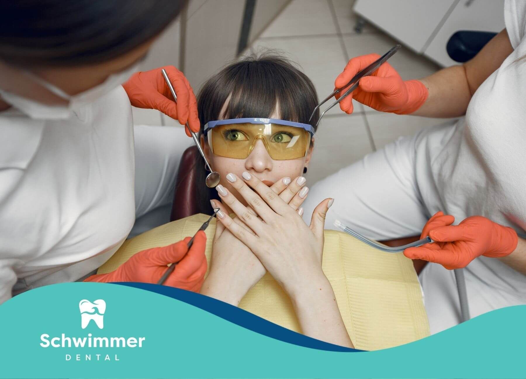 A patient sitting in a dental chair with her hands over her mouth, feeling anxious about the dentist