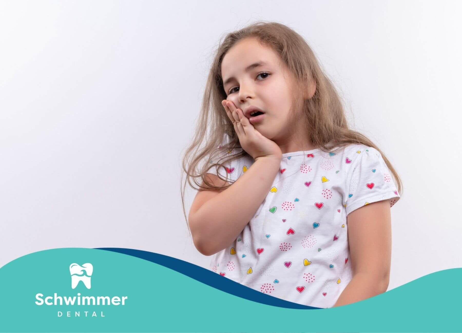 Young girl touching cheek with toothache expression.