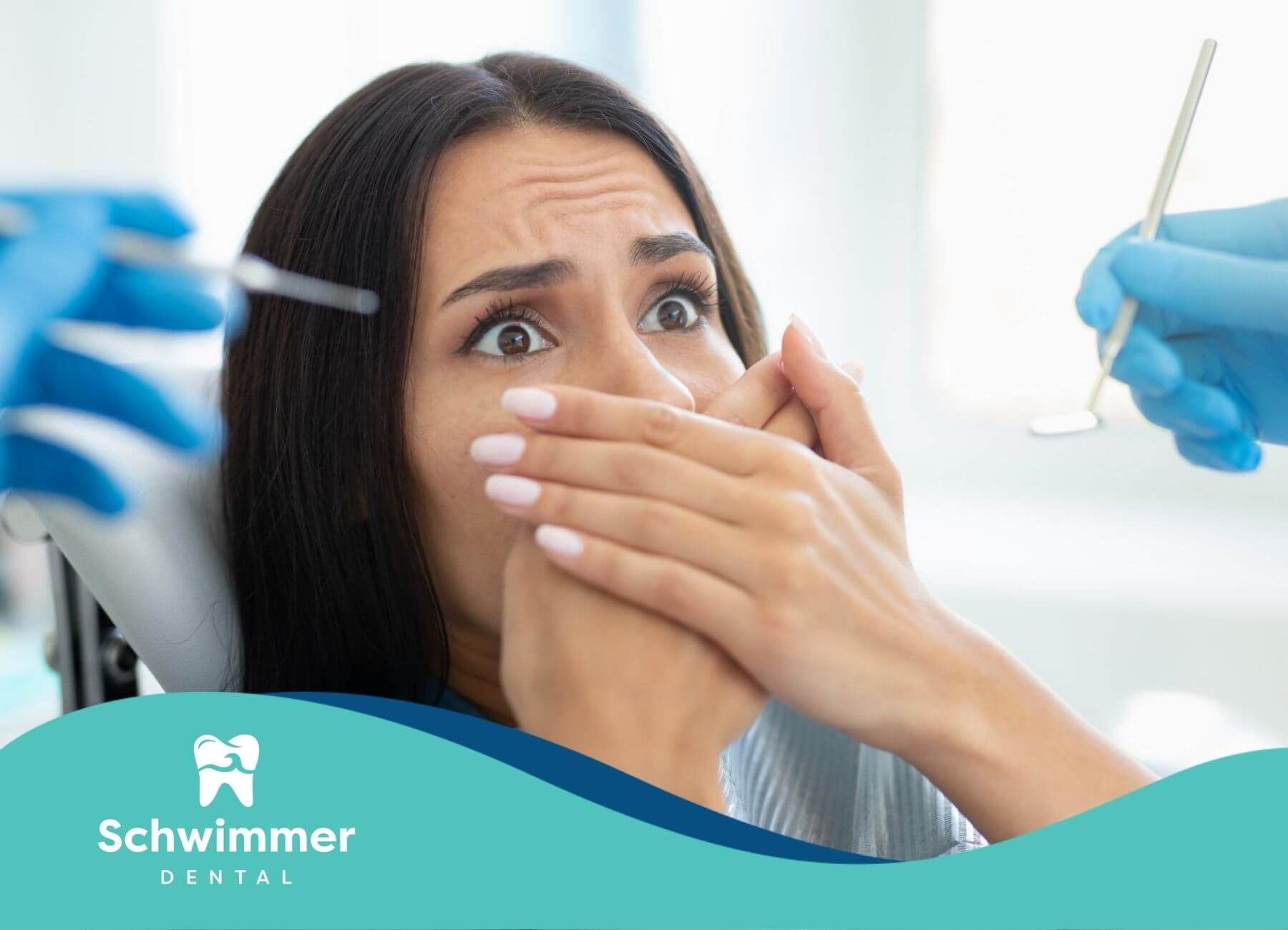 Frightened woman covering her mouth in a dental chair.

