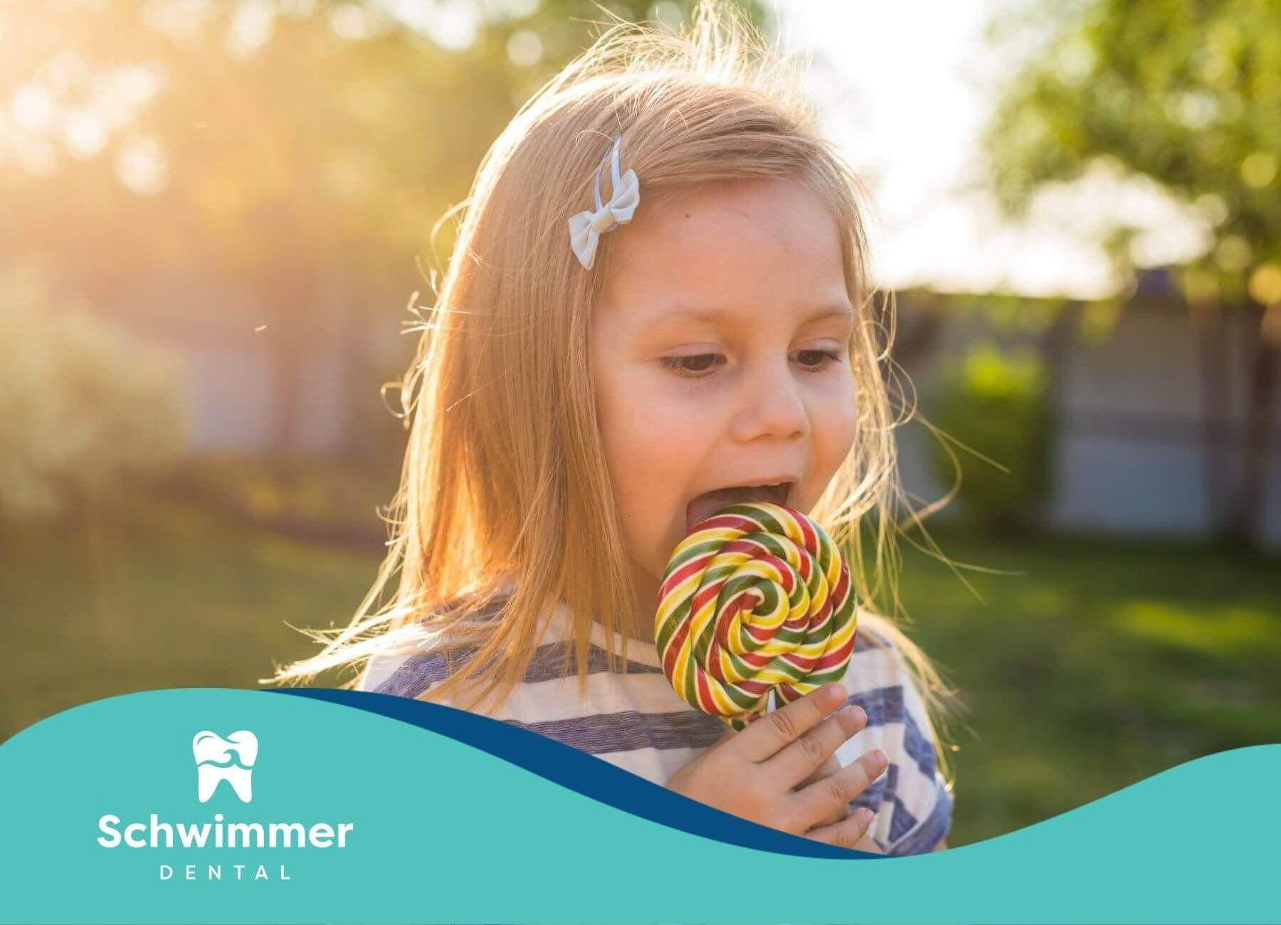 Little girl enjoying a large, colorful lollipop outside.