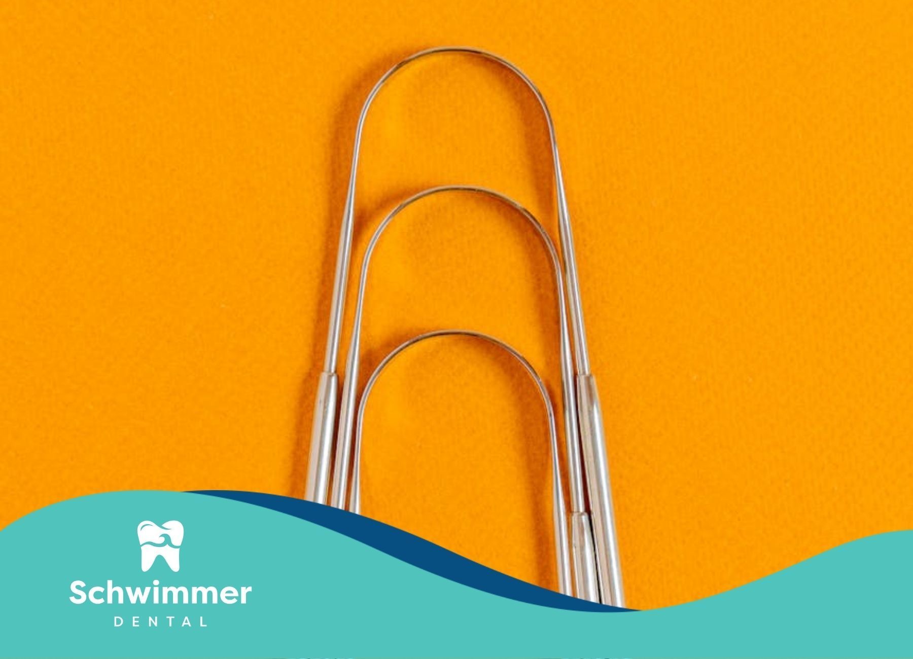 Three stainless steel tongue scrapers arranged on orange background at a dental clinic in New Jersey