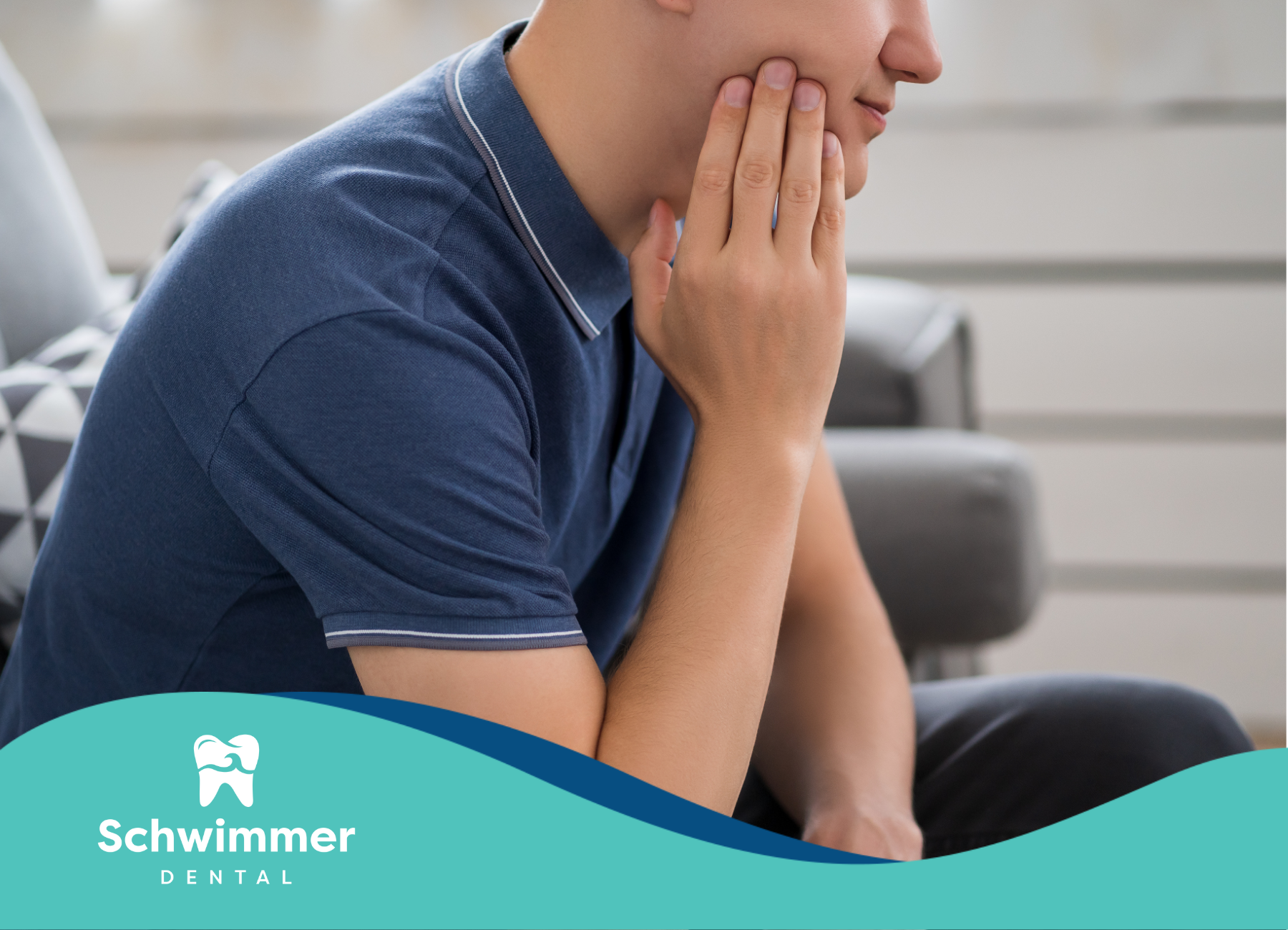 A man is sitting on a couch with his hand on his face.