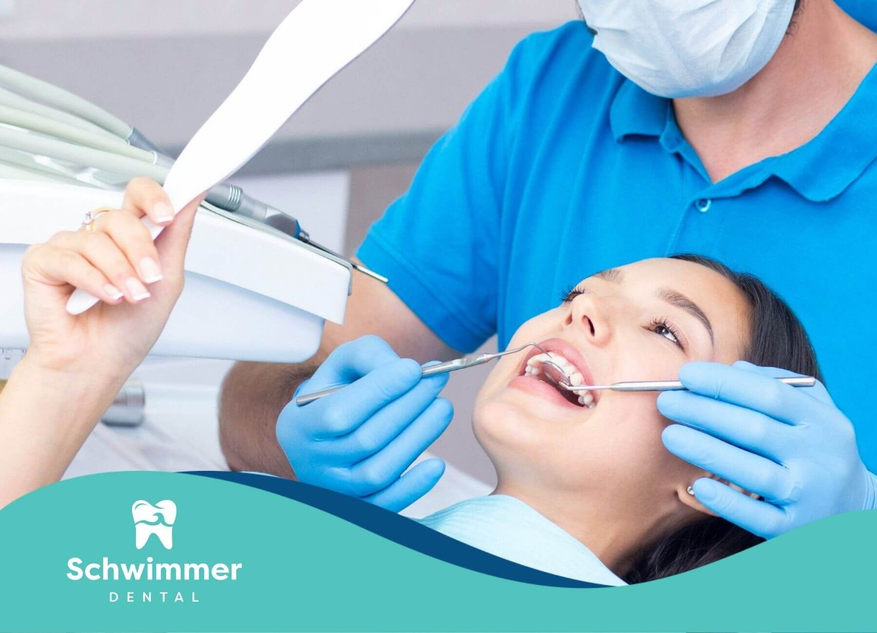 A woman is looking at her teeth in the mirror during deep dental cleaning appointment.