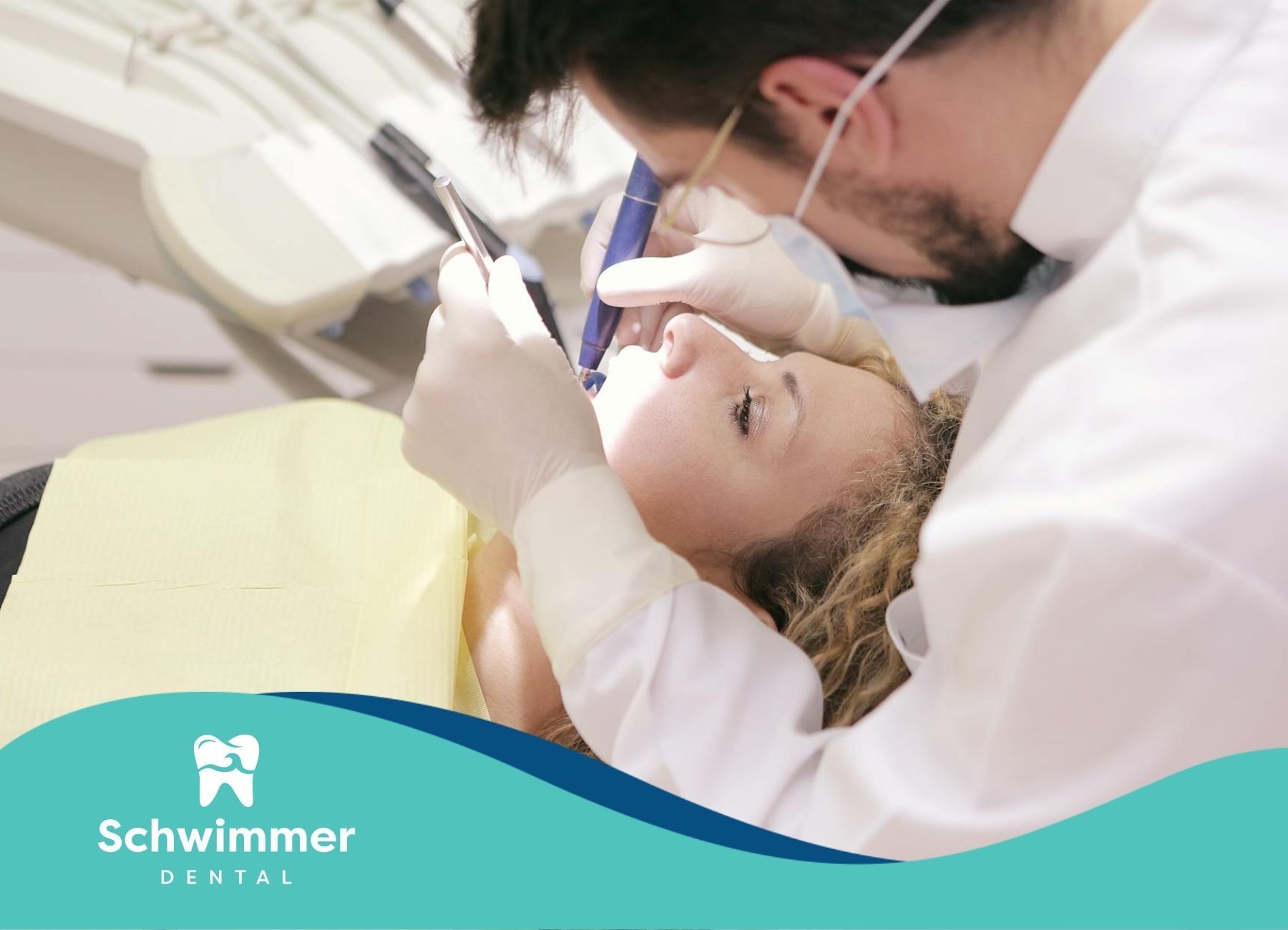 Dentist working on tooth extraction of a patient in the dental chair while wearing protective gear.