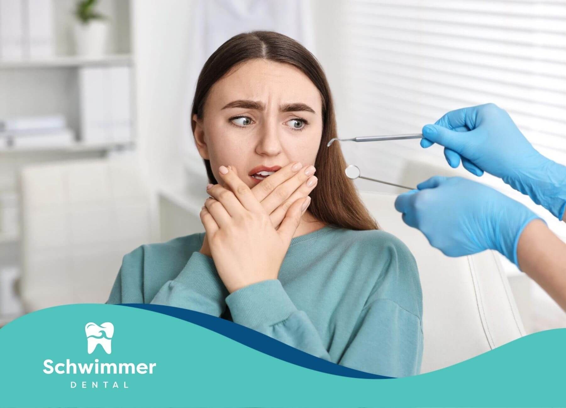 Woman with fearful expression covering her mouth as gloved hands hold ear-piercing equipment.