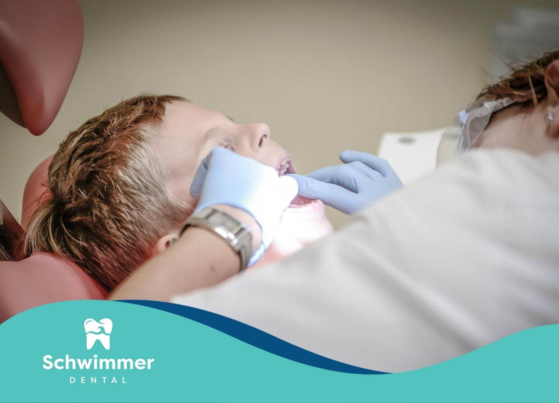 A dentist gently examines a young boy’s teeth during a routine dental check-up in a clinic setting.