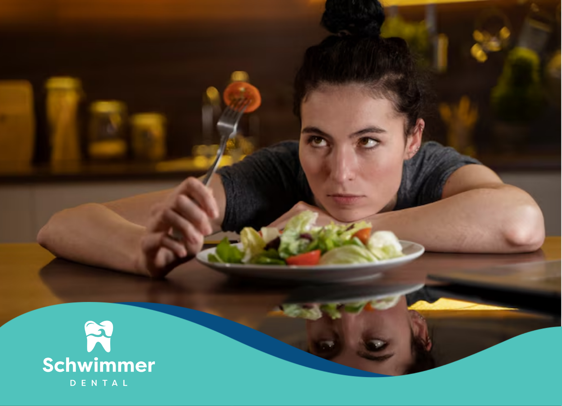 A woman is sitting at a table eating a salad with a fork.