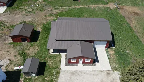 Overhead view of a house with attached garage, a small shed, and another shed on a grassy property.
