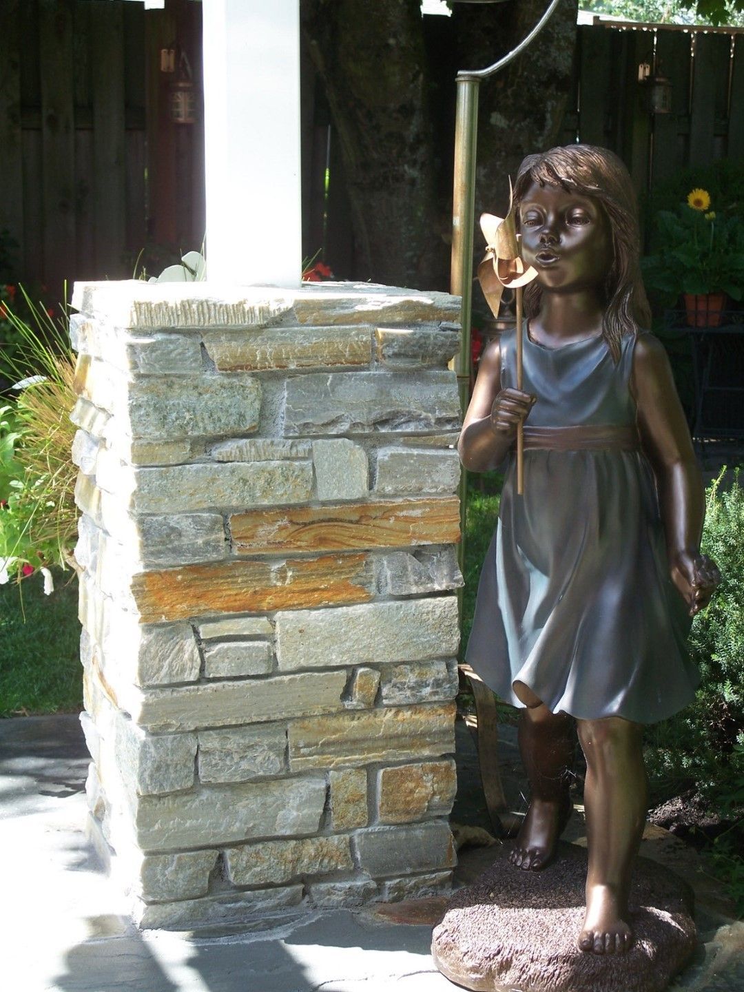 A statue of a girl standing next to a stone wall