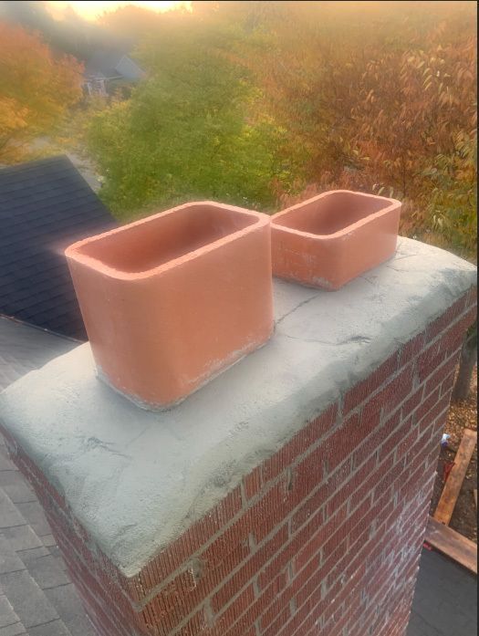 Two pots are sitting on top of a brick chimney.