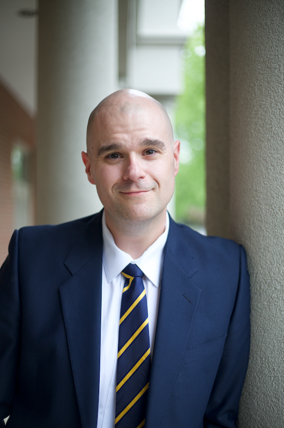 A man in a suit and tie is leaning against a wall.