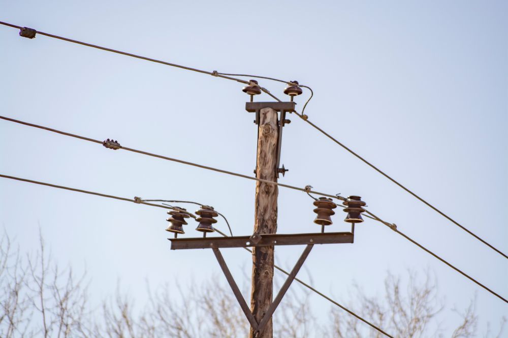 Wooden Utility Pole With Electrical Wires, Against a Pale Blue Sky — Bennett's Tree Service in Lake Macquarie, NSW